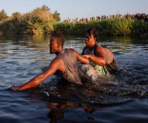 Dos migrantes haitianos cruzan el río Bravo desde Del Río, Texas, hacia Ciudad Acuña, México, el lunes 20 de septiembre de 2021 para evitar ser deportados por Estados Unidos. (AP Foto/Félix Márquez).