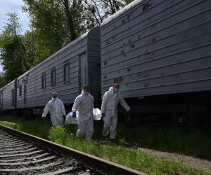 Expertos forenses ucranianos llevan el cuerpo de un soldado ruso exhumado en la aldea de Zavalivka, al oeste de Kiev, antes de almacenarlo en un vagón refrigerado lleno de rusos muertos el 11 de mayo de 2022.