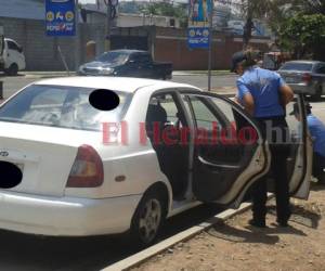 Agentes de la Dirección Policial de Investigaciones (DPI) realizan pesquisas en un taxi que fue víctima de un asalto en la capital. Foto archivo EL HERALDO