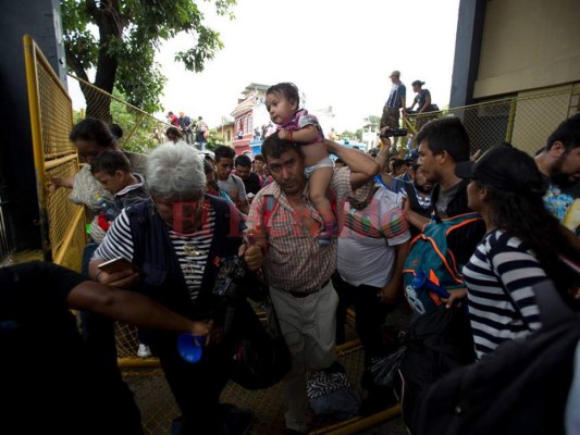 Los migrantes hondureños cruzaron la frontera hacia México, Tecun Uman, Guatemala, viernes 19 de octubre de 2018. Los migrantes rompieron el puente hacia México. (Foto AP / Moises Castillo).