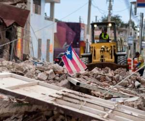 En esta foto de archivo tomada el 8 de enero de 2020, una bandera puertorriqueña ondea sobre una pila de escombros mientras se retiran los escombros de una carretera principal en Guánica, Puerto Rico, después del terremoto del 7 de enero. Foto AFP