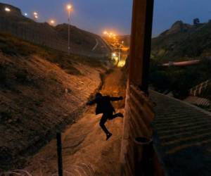 En esta fotografía de archivo del viernes 21 de diciembre de 2018, un joven hondureño salta a territorio estadounidense desde la valla fronteriza en Tijuana, México.