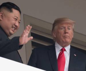 El líder de Corea del Norte Kim Jong Un saluda mientras él y el presidente estadounidense Donald Trump miran desde una terraza durante su histórica cumbre entre EE. UU.