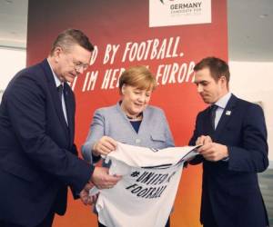 La canciller alemana, Angela Merkel; el titular de la Federación Alemana de Fútbol, ​​Reinhard Grindel y el exfutbolista Philipp Lahm, promocionan el Campeonato Europeo de Fútbol 2024 en Berlín. (AP)