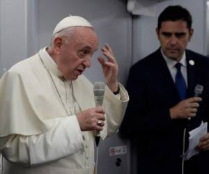 El Papa Francisco, flanqueado por el portavoz del Vaticano Alessandro Gisotti, gesticula mientras responde a las preguntas de los periodistas en el avión tras el despegue de la ciudad de Panamá.