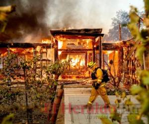 El bombero Joe Zurilgen camina frente a una casa envuelta en llamas en Healdsburg, California, el domingo 27 de octubre de 2019. AP Foto/Noah Berger