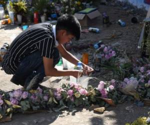 Un niño encienden una veladora en el sitio donde ocurrió el fatal accidente que dejó a 56 migrantes, en su mayoría guatemaltecos, muertos. FOTO: AFP