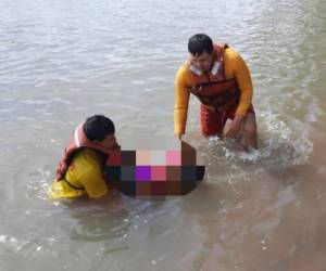 Los rescatistas cargan el cuerpo de la pequeña niña hasta la orilla del río.