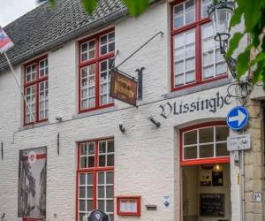 La fachada de Café Vlissinghe exhibe una bandera del pueblo de Brujas, un rótulo antiguo con su nombre y un menú que destaca sus meriendas estrellas.