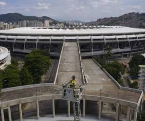 Con el estadio Maracaná de fondo, el bombero Elielson Silva toca su trompeta desde lo alto de la escalera desplegada de su camión en Río de Janeiro. Foto: AP.