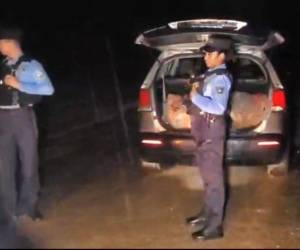 Agentes policiales resguardan la escena donde fue localizada una camioneta con dos personas sin vida en su interior, en un sector de La Ceiba.