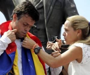 Leopoldo López, un ardiente opositor del gobierno socialista de Venezuela que enfrenta una orden de arresto después de que el presidente Nicolás Maduro ordenó su arresto por homicidio e incitación a la violencia, recibe un collar de Cristo de su esposa Lilian Tintori, durante una manifestación antes de entregarse. Autoridades, en Caracas.