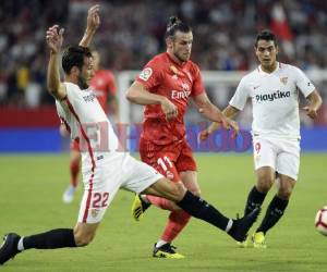 Con este resultado, que saca al Leganés provisionalmente del descenso, El delantero gaélico del Real Madrid Gareth Bale (C) compite con el mediocampista italiano del Sevilla Franco Vázquez (L) durante el partido de fútbol de la liga española Sevilla FC contra el Real Madrid CF en el estadio Ramón Sánchez Pizjuán de Sevilla el 26 de septiembre de 2018. (AFP)