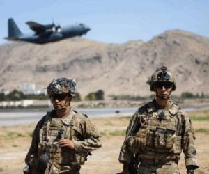 En esta imagen difundida por el Departamento de Defensa, dos soldados asignados a la 1ra Brigada de Combate de la 82da División Aérea realizan una inspección de seguridad mientras un Hercules C-130 despega durante la operación de evacuación, el miércoles 25 de agosto de 2021, en Kabul, Afganistán. (Department of Defense via AP)