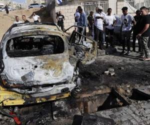 Onlookers gather around charred vehicles hit by rockets launched by Hamas militants from the Gaza Strip in the southern Israeli city of Ashkelon on the border with the Palestinian coastal enclave on May 16, 2021. (Photo by JACK GUEZ / AFP)