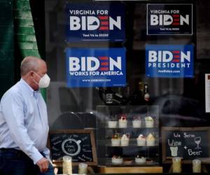 Un hombre con una máscara facial pasa junto a las señales de la campaña presidencial 2020 de Joe Biden en medio del brote de coronavirus el 11 de mayo de 2020 en Alexandria, Virginia. Foto: Agencia AFP.