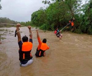 Un residente avanza por una cuerda mientras rescatistas esperan al otro lado de un río cuyo caudal aumentó notablemente por las fuertes lluvias de la tormenta tropical Kompasu, en Gonzaga, en la provincia de Cagayan, en el norte de Filipinas. FOTO: AP