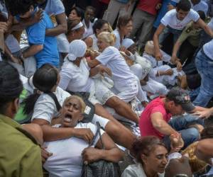 Las mujeres ante la llegada de la policía, se sentaron en el suelo para intentar evitar su traslado, en medio del acoso de los manifestantes a favor del gobierno que les gritaban 'mercenarias' y 'gusanas' (anticastristas)