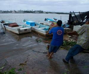 Los pescadores intentan tirar de un bote que fue inundado por el huracán Rick en Lázaro Cárdenas, México, el lunes 25 de octubre de 2021. Foto: AP