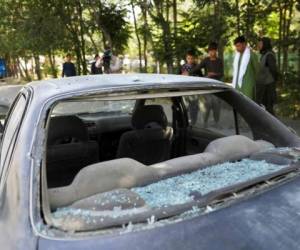 Hombres afganos miran a un auto dañado tras la explosión de una bomba caminera en Kabul, Afganistán, el domingo 6 de junio de 2021. Foto: AP