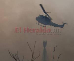 Un helicóptero de la Fuerza Aérea Hondureña (FAH) lanza agua desde el aire para apagar las llamas que consumen el bosque de la capital de Honduras. Foto: Emilio Flores/EL HERALDO.