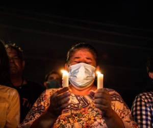 Una mujer que sostiene velas llora mientras observa cómo el resto de la torre Champlain South es demolido por una explosión controlada en Surfside, Florida, al norte de Miami Beach, a última hora del 4 de julio de 2021. Foto: AFP