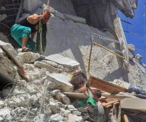 La instantánea muestra a Riham, de cinco años, sujetando de la camiseta desgarrada a Tuka, de siete meses, a punto de caer, mientras que Dalia, a su lado, parece estar atrapaba bajo un escombro de cemento. Foto: Agencia AP.