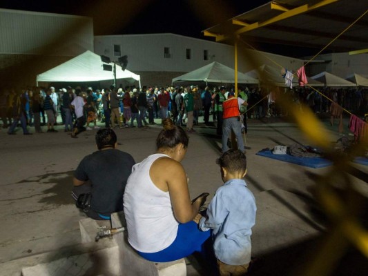 Los inmigrantes centroamericanos se alinean para comer y descansar en colchones dentro de una bodega utilizada como albergue en Piedras Negras Coahuila, México.