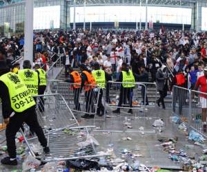 En esta foto del 11 de julio de 2021, empleados de seguridad reacomodan las barricadas derribadas por hinchas ingleses previo a la final del Campeonato Europeo en el estadio Wembley. Foto:AP