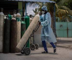 Un empleado de hospital con equipo para protegerse del COVID-19 transporta tanques de oxígeno en Puerto Príncipe, Haití. (AP Foto/Joseph Odelyn, archivo).