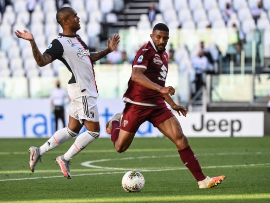 El alero brasileño de la Juventus Douglas Costa y el defensor brasileño de Torino Bremer van por el balón durante el partido de fútbol de la Serie A italiana Juventus vs Torino jugó a puerta cerrada. Foto: Agencia AFP.