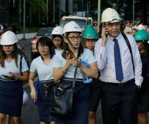 Oficinistas usando cascos desalojan el edificio donde trabajan después de un sismo de magnitud 6,1 en Manila, Filipinas, el 22 de abril de 2019. (AP Foto/Aaron Favila)