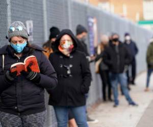 Ashley Gannon, izquierda, lee mientras espera en fila el jueves 19 de noviembre del 2020 afuera de un sitio de pruebas de coronavirus en Brooklyn, Nueva York.