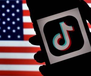 El logotipo de la aplicación de redes sociales TikTok se muestra en la pantalla de un iPhone sobre un fondo de bandera estadounidense en Arlington, Virginia. Foto: Agencia AFP.
