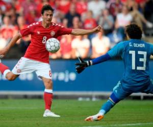 El danés Thomas Delaney intenta marcar contra el guardameta mexicano Guillermo Ochoa. Foto AFP