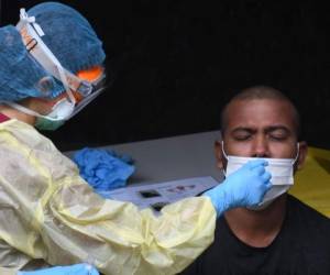 Un trabajador de la salud vestido con equipo de protección personal recolecta una muestra de hisopo nasal de un trabajador migrante para analizar el nuevo coronavirus Covid-19 en un territorio de trabajadores. Foto: Agencia AFP.