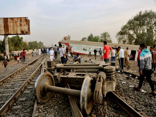 Unas personas observan los restos de un tren descarrilado cerca de Banha, en Egipto, que dejó al menos 11 personas muertas y decenas de heridos, el 18 de abril de 2021. (AP Foto/Fadel Dawood).