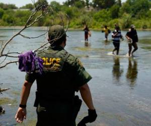 Un agente de la Patrulla Fronteriza de Estados Unidos junto con migrantes que cruzan el río Bravo cerca de Del Rio, Texas, el 15 de junio de 2021. Foto: AP