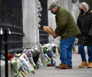 Un hombre deja un ramo de flores en la puerta del Palacio de Buckingham, en Londres, el 10 de abril de 2021, un día después de la muerte del príncipe Felipe, el marido de la reina Isabel II. Foto: AP