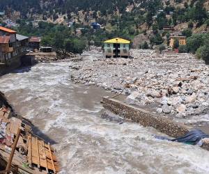 El agua de la inundación fluye junto a un mercado dañado al borde de la carretera tras las inundaciones repentinas en Parun, provincia de Nuristán, en el este de Afganistán, el 21 de julio de 2026.