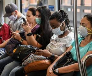 La gente usa máscaras faciales contra la propagación del nuevo coronavirus en el metro de Medellín, Colombia. Foto AFP