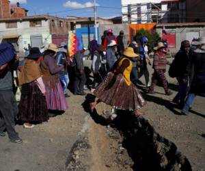 Los partidarios del expresidente Evo Morales pasan por una zanja excavada para evitar que los vehículos pasen por la carretera que conduce a la planta 'Yacimientos Petrolíferos Fiscales Bolivianos' en El Alto. Foto: AP.