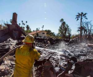Los bomberos luchan contra los puntos calientes en Viento Way después de que varias casas fueron incendiadas por el incendio de Hillside en San Bernardino, California, el 31 de octubre de 2019.