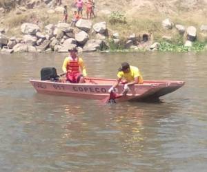 Miembros de Copeco realizan el levantamiento del cadáver del joven de 18 años ahogado en el río Chamelecón.