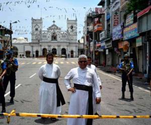 Los soldados hacen guardia mientras los sacerdotes hablan con los residentes locales fuera del Santuario de San Antonio en Colombo el 25 de abril de 2019.