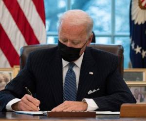 El presidente de los Estados Unidos, Joe Biden, firma una Orden Ejecutiva que revierte la prohibición de la era Trump de que las personas transgénero sirvan en el ejército mientras se encuentran en la Oficina Oval de la Casa Blanca en Washington, DC, el 25 de enero de 2021. Foto: AFP