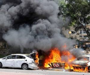 Una foto tomada el 11 de mayo de 2021 muestra automóviles en llamas después de que un cohete lanzado desde la Franja de Gaza, controlado por el movimiento palestino Hamas, aterrizara en la ciudad de Ashkelon, en el sur de Israel. Foto: AFP