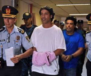 El exastro brasileño de fútbol Ronaldinho camina esposado a una audiencia judicial en Asunción, Paraguay, el sábado, 27 de marzo del 2020.