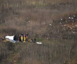 Cuadrillas de emergencias cubren un cadáver, junto al lugar donde se encuentra otro, tras la caí­da de un helicóptero, en que murió el basquetbolista retirado Kobe Bryant, en Calabasas. Foto: AP.