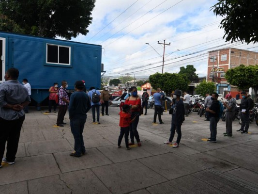 Personas con síntomas de la cola de coronavirus fuera de una unidad del Instituto Hondureño de Seguridad Social (IHSS) en Tegucigalpa. Foto: Agencia AFP.